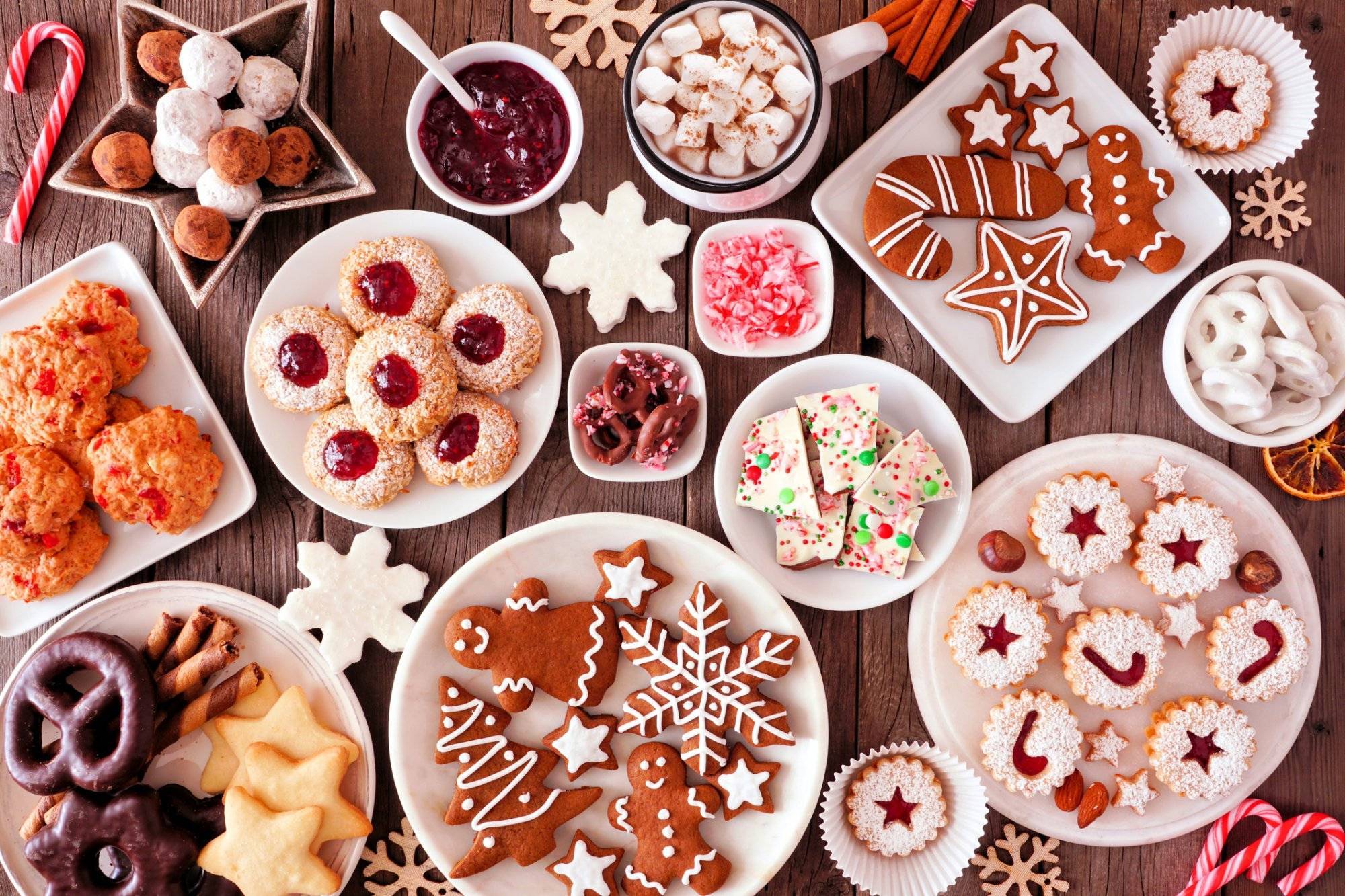 Christmas baking table scene with assorted sweets and cookies, top view over a rustic wood background